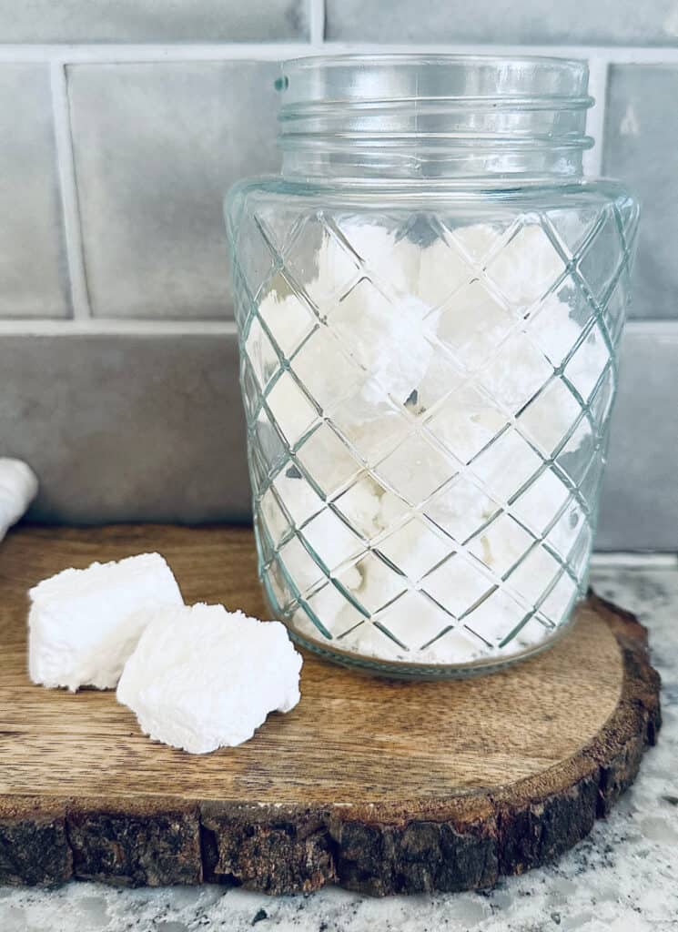 Homemade toilet cleaner tablets in a glass storage jar.